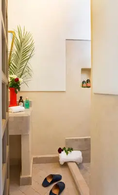 a bathroom with a sink and a toilet with flip flops at Riad Lumière in Marrakech