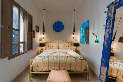 a bedroom with a gold frame bed and a window at Riad Lumière in Marrakech