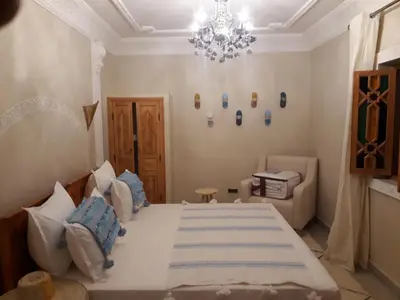 a bedroom with a large bed and a chandelier at Riad azra Marrakech in Marrakech