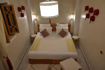 a small bedroom with a bed with white sheets and pillows at Riad azra Marrakech in Marrakech