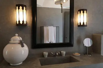 a bathroom with a sink with a mirror and a vase at Dar Seven in Marrakech