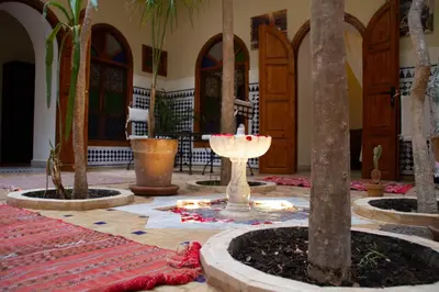 a lobby with palm trees and a fountain in a building at Riad Dar Tamlil in Marrakech