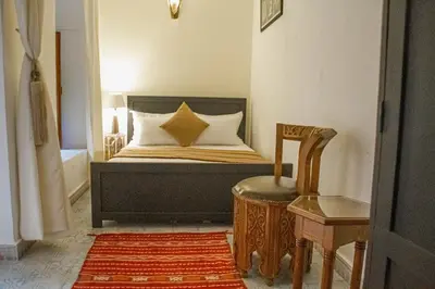a bedroom with a bed with a chair and a stool at Riad Dar Tamlil in Marrakech
