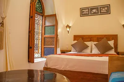 a bedroom with a bed with a table and a window at Riad Dar Tamlil in Marrakech