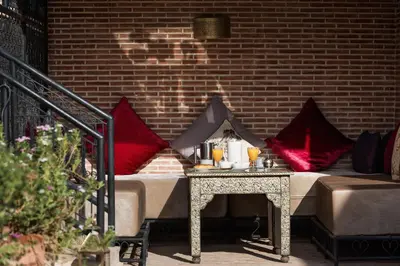 a bed with red pillows sitting next to a brick wall at Riad Spice by Marrakech Riad in Marrakech