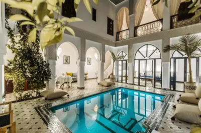 a swimming pool in a building with a house at Riad NayaNour in Marrakech