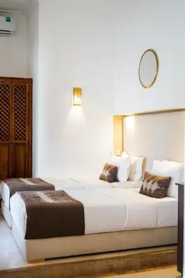a bedroom with two beds and a mirror on the wall at Riad NayaNour in Marrakech