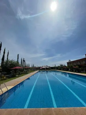 a large swimming pool with the sun in the sky at Palais Benfatah in Marrakech