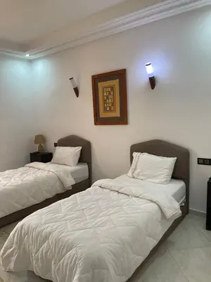 a bedroom with two beds and a picture on the wall at Palais Benfatah in Marrakech