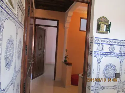 a hallway with a door and a room with blue and white tiles at Zwina Appart, A Small, Cozy Family Nest in Marrakech