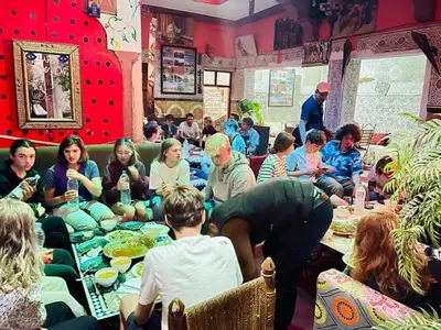 a group of people sitting around tables eating food at Hostel Marrakech Rouge in Marrakech