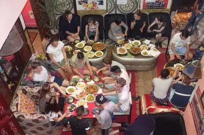a group of people sitting around a table with food at Hostel Marrakech Rouge in Marrakech