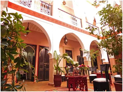 a courtyard with plants and a table with flowers at Riad La Rose D'orient in Marrakech