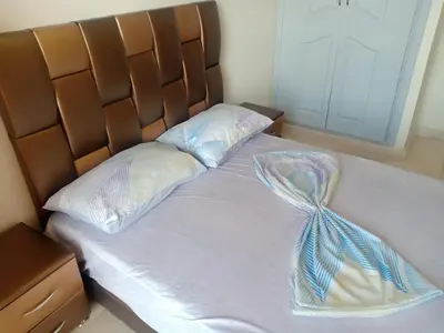 a bed with a brown headboard with a blue ribbon on it at Appartement rouge 6 perso in Marrakech
