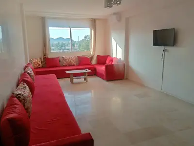 a living room with a red couch and a tv at Appartement rouge 6 perso in Marrakech