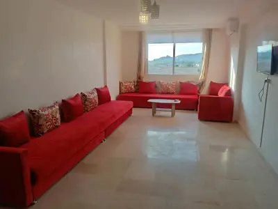 a living room with a red couch and a table at Appartement rouge 6 perso in Marrakech