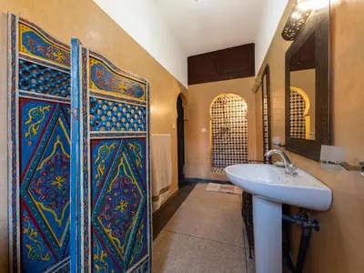 a bathroom with a sink and a wall with a shower at Villa Soraya Hammam & Jacuzzi in Marrakech