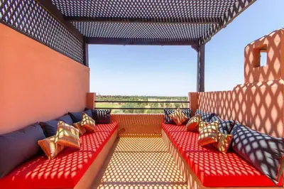 a balcony with red benches with gold pillows at VILLA Waky & Golf - Jardin de l'Atlas in Marrakech