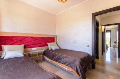 a bedroom with two beds and a red headboard at VILLA Waky & Golf - Jardin de l'Atlas in Marrakech