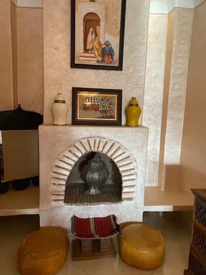a living room with a brick fireplace with two stools at Riad Lalla Merieme in Marrakech