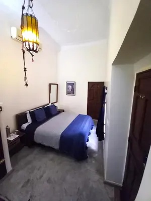 a bedroom with a bed with blue pillows and a chandelier at Riad Alqimam in Marrakech