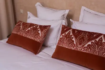 a bed with white pillows and brown and white pillows at RIAD AZRUR in Marrakech