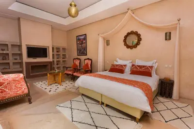 a bedroom with a large bed and a tv at RIAD AZRUR in Marrakech