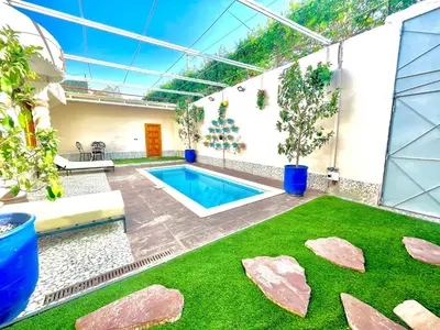 a swimming pool in a house with a green lawn at Villa Paradis in Marrakech