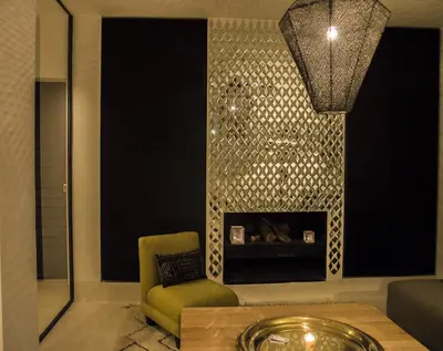a living room with a fireplace and a green chair at Douiria13 in Marrakech