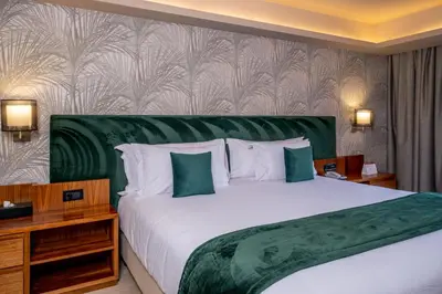 a bedroom with a large bed with a green headboard at Kenzi Rose Garden in Marrakech