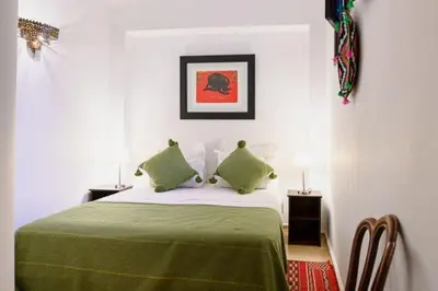 a bedroom with a bed with two green pillows at Riad Zouhour in Marrakech
