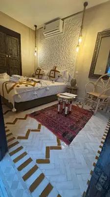 a bedroom with a bed and a table and a rug at Riad Beata Bed & Breakfast in Marrakech