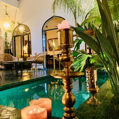 a room with a swimming pool with a table and a mirror at Riad Dar Yasaman in Marrakech