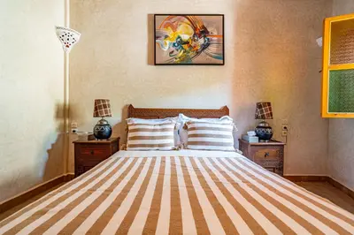 a bedroom with a large bed with a striped bedspread at RIAD VILLA SIDI BABA in Marrakech