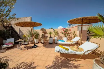 a patio with chairs and umbrellas and the ocean at Riad 7 Saints in Marrakech