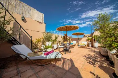 a patio with chairs and tables and umbrellas at Riad 7 Saints in Marrakech