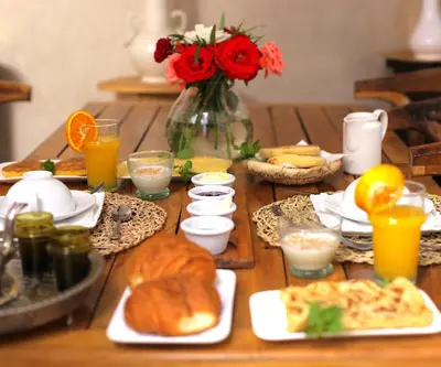 a table topped with plates of food and orange juice at Riad 7 Saints in Marrakech