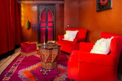 a living room with red chairs and a table at Riad Touda in Marrakech