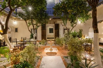 a courtyard with tables and chairs and trees at Riad Tchaikana in Marrakech