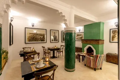 a restaurant with a green column and tables and a fireplace at Riad Hart Essoura in Marrakech