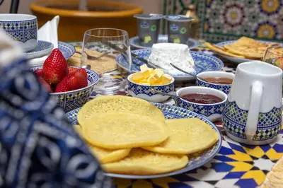 a table topped with blue and white plates with pancakes and strawberries at Riad Hart Essoura in Marrakech