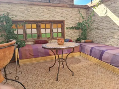 a room with a table and a couch and windows at Riad BAB ALMADINA in Marrakech