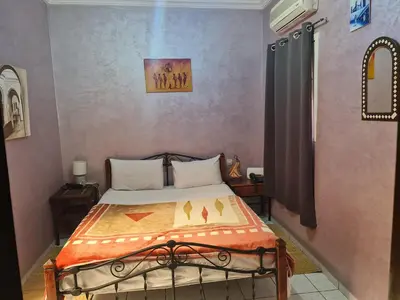 a bedroom with a bed with an orange blanket at Riad BAB ALMADINA in Marrakech