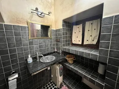 a black tiled bathroom with a sink and a mirror at Dar KHALID in Marrakech