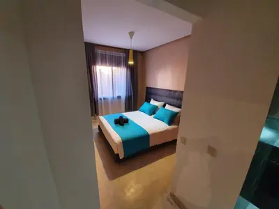 a bedroom with a bed with blue pillows at Charming Marrakech Apartement in Marrakech