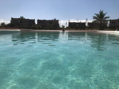 a pool of clear blue water in front of a beach at Villa Mayrit, Villa estilo Riad en un entorno único in Marrakech