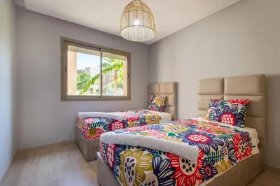 a bedroom with two beds and a window at Pool View With Garden in Prestigia - WIFI & Pool in Marrakech