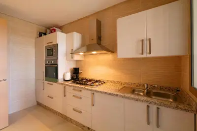 a kitchen with white cabinets and a sink at Escale de Charme - Prestigia Golf - Vue piscine in Marrakech