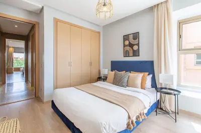 a bedroom with a large bed with a blue headboard at Escale de Charme - Prestigia Golf - Vue piscine in Marrakech