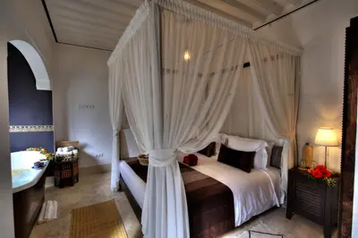 a bedroom with a canopy bed and a sink at Riad Mazarin des gourmets in Marrakech